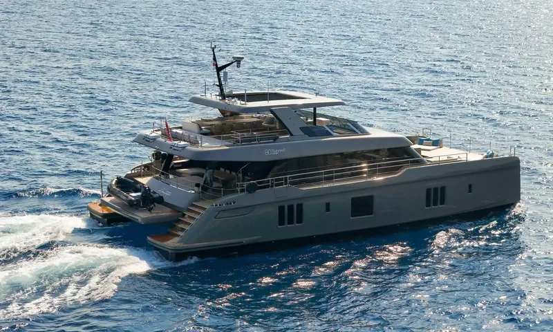 Amitatu: Grey power catamaran under way with a tender on the stern platform
