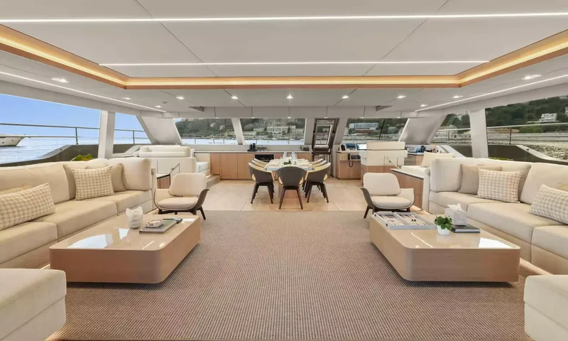 Amitatu: Wide bright saloon with cream sofas, coffee tables and a dining table beyond