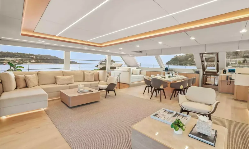 Amitatu: Saloon with corner sofa, armchairs and dining area beside large windows on the water