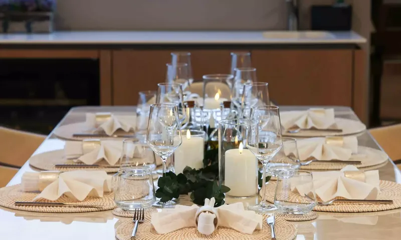 Amitatu: Close view of a table set with glasses, folded napkins, woven placemats and candles