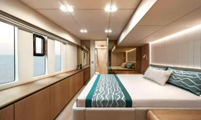 Amitatu: Cabin with double bed, teal bed runner, sea view windows and ensuite beyond