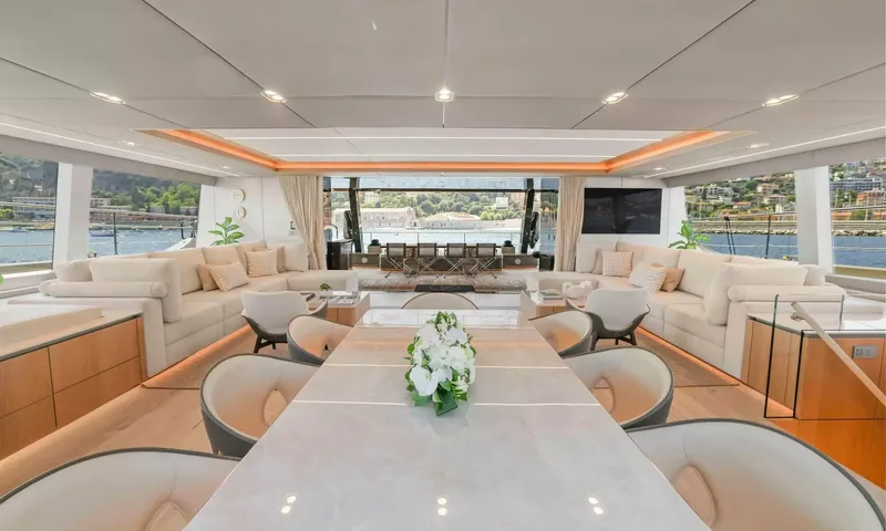 Amitatu: Long dining table with flowers leading to a saloon with sofas and harbor views