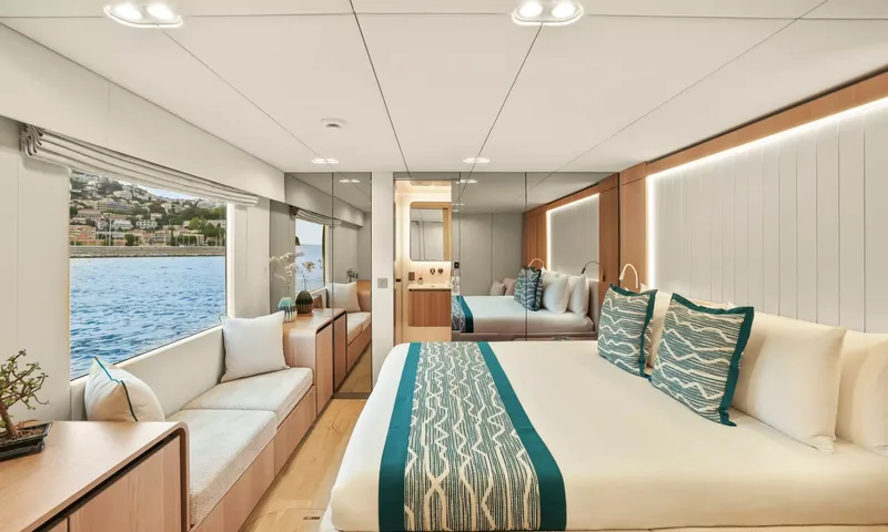 Amitatu: Double cabin with teal cushions, mirrored wardrobe and window seat facing the sea