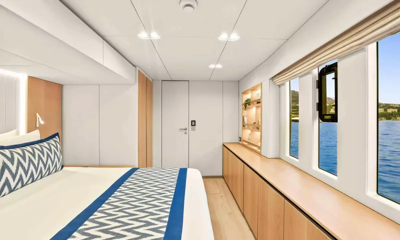 Amitatu: Cabin with blue patterned bedding, long wooden cabinet and row of windows