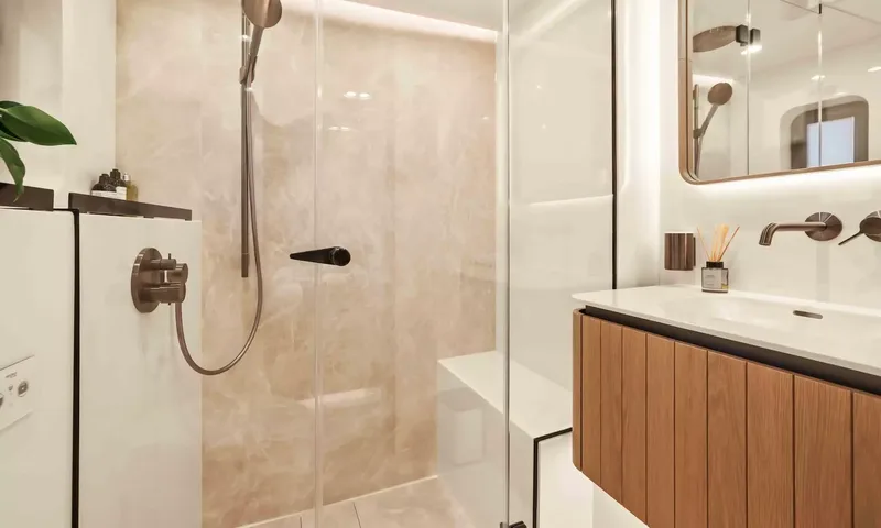 Amitatu: Walk in shower with stone walls beside a wooden vanity and sink