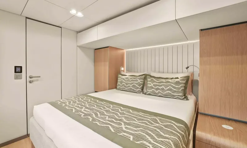 Amitatu: Compact cabin with double bed, green patterned cushions and wooden wardrobe
