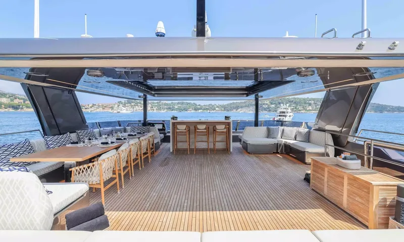 Amitatu: Shaded upper deck with dining table, bar stools and lounge sofa above the bay