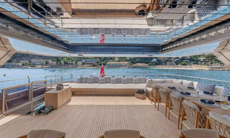 Amitatu: Upper deck with set dining table, bench seating and dumbbells under a hardtop