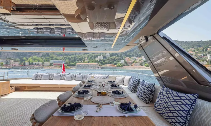 Amitatu: Outdoor dining table laid with navy napkins beside patterned cushions and a sea view