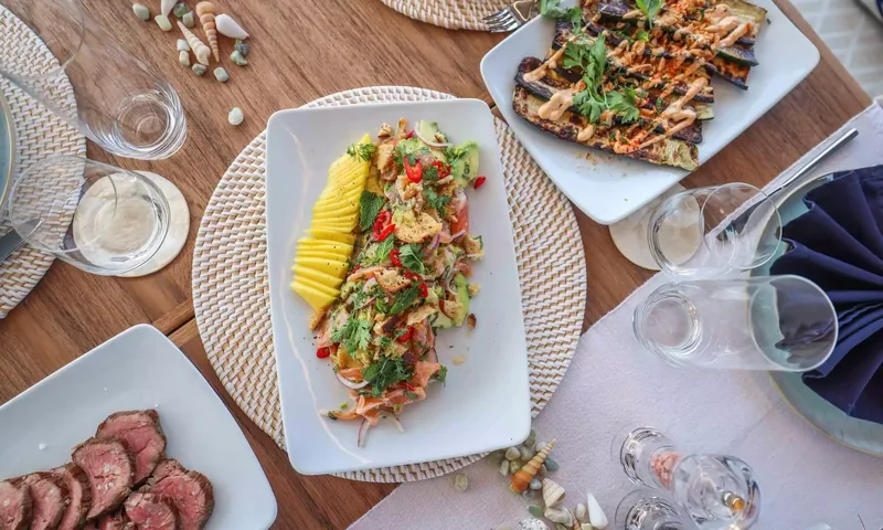 Amitatu: Overhead view of plated salad, grilled vegetables and sliced beef on a wooden table