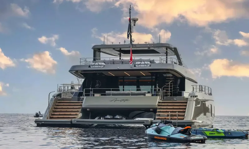 Amitatu: Stern of a catamaran at sunset with jet ski and towable floating nearby