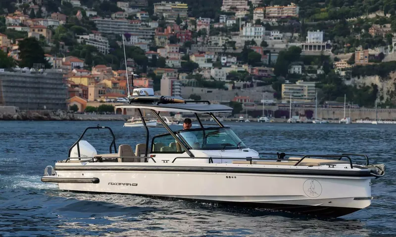 Amitatu: White tender with shaded console cruising past a hillside town