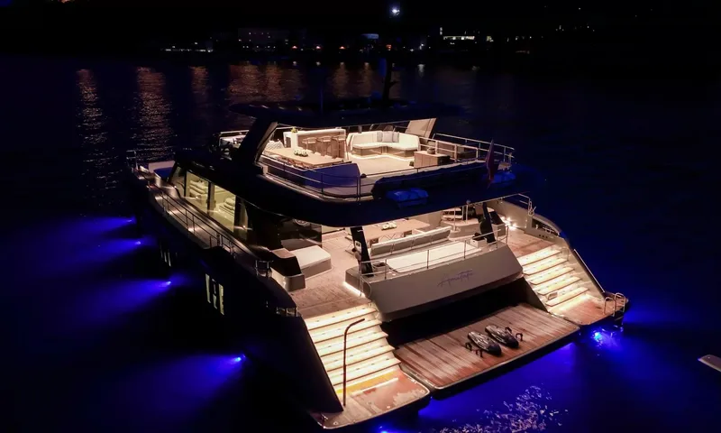 Amitatu: Catamaran at night seen from above, lit decks, stern platform and blue underwater lights