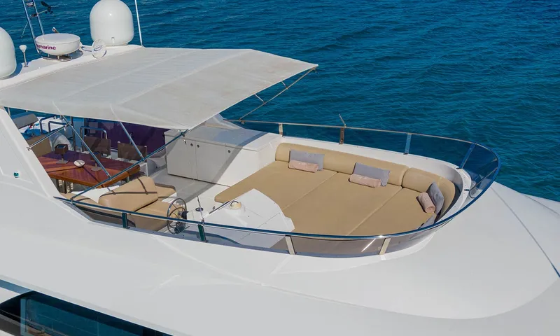 Enjoy I: Flybridge com grande colchonete de sol bege, leme, mesa de jantar com sombra e mar abaixo