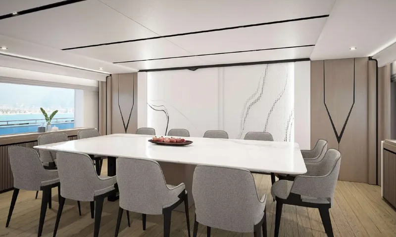 Yoto: Indoor dining table with ten grey chairs beside a window overlooking the sea
