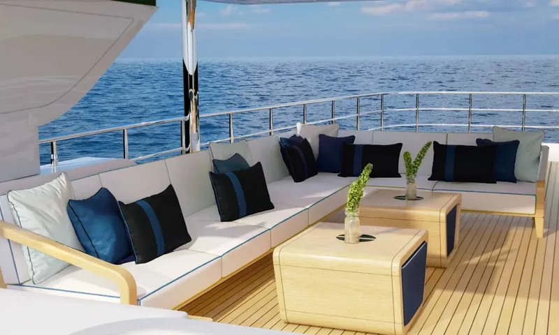 Yoto: Outdoor lounge with long white sofa, blue cushions and wooden tables by the sea