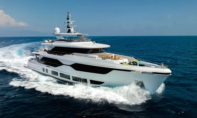 Yoto: White and black yacht cruising at speed on deep blue sea, guests relaxing on the foredeck