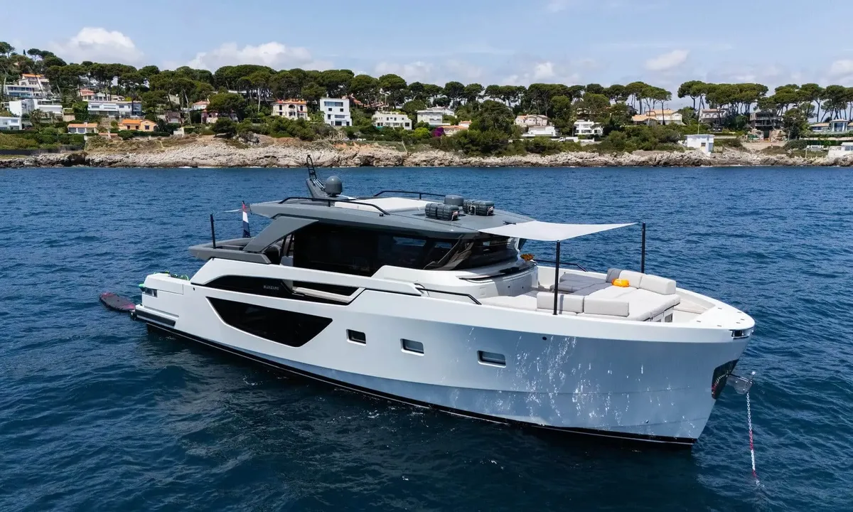 Jamon: White motor yacht at anchor near a rocky wooded coastline with a shaded foredeck lounge