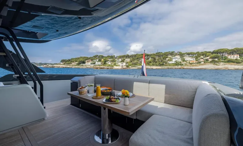 Jamon: Outdoor table set with food and drinks beside curved seating, coastline in the background