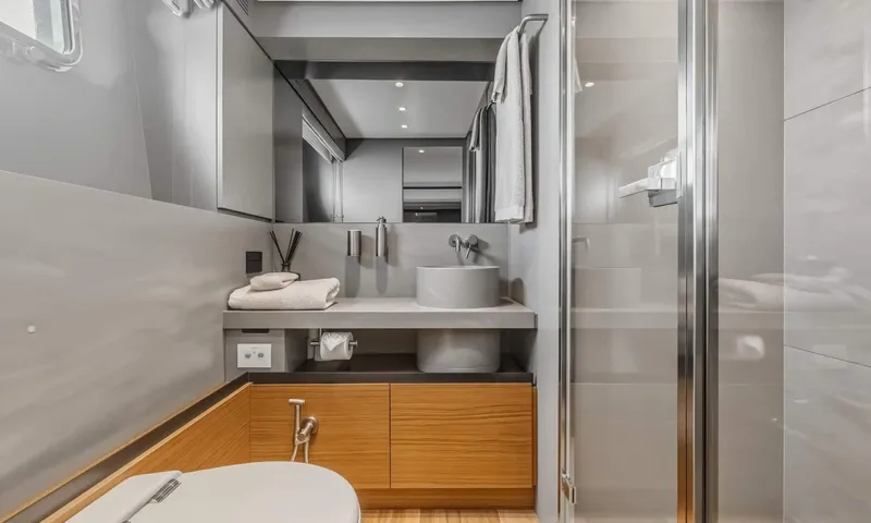 Jamon: Grey bathroom with vessel sink, wooden vanity, mirror and glass shower