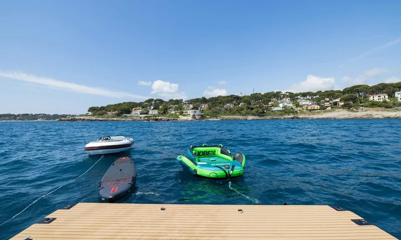 Jamon: Small tender, paddleboard and inflatable towable floating behind a teak platform