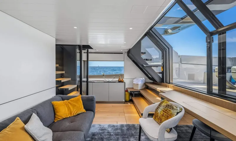 Jamon: Lounge with grey sofa, armchair, desk and staircase beside large sea view windows