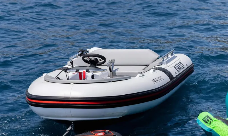 Jamon: Small grey inflatable tender with steering wheel floating on blue water
