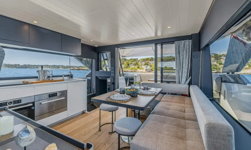 Jamon: Galley with ovens beside a dining table and grey bench seating with sea views