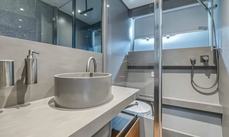 Jamon: Bathroom with round grey basin, soap dispenser and glass shower enclosure