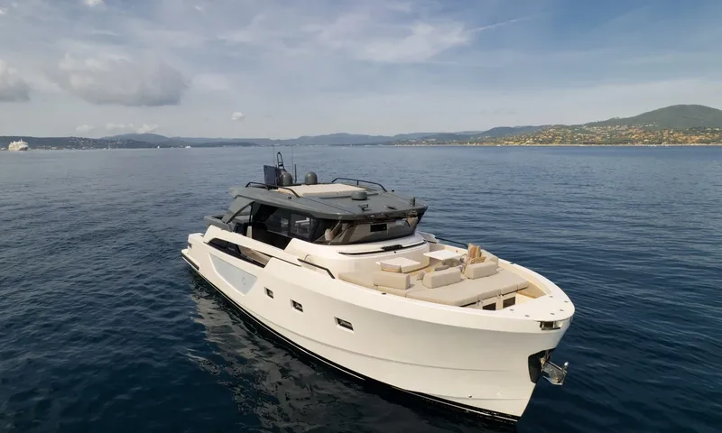 CC: White motor yacht at anchor seen from above, foredeck lounge facing the hilly coast