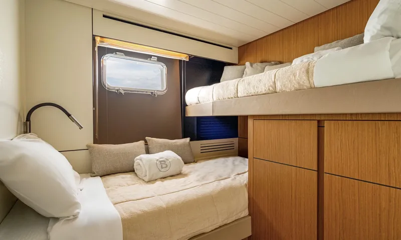 CC: Twin cabin with bunk style beds, wooden cupboards and a porthole window