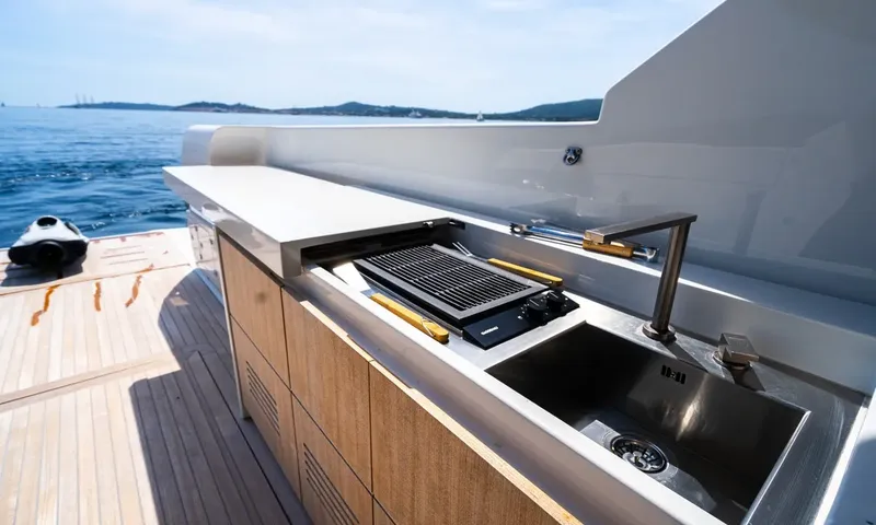 CC: Outdoor counter with built in grill and steel sink beside a teak deck