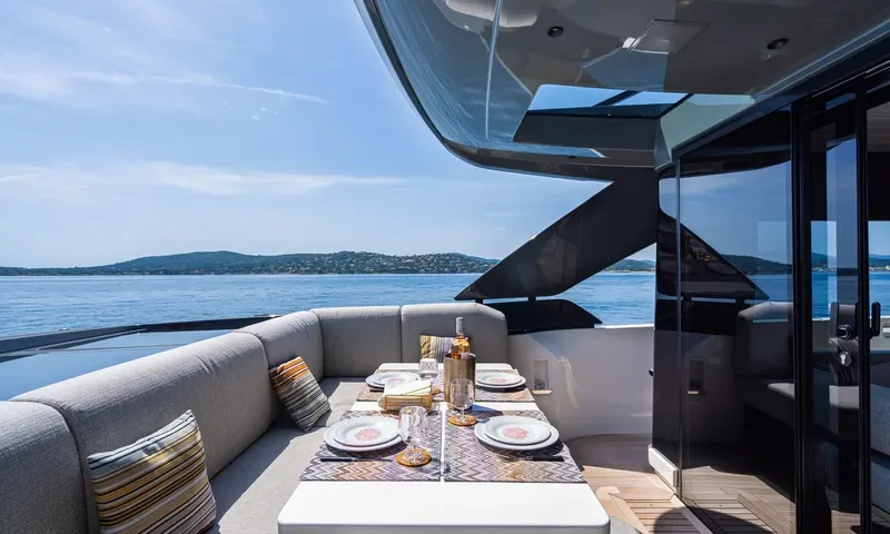 CC: Set outdoor dining table with grey sofa seating and striped cushions overlooking the sea