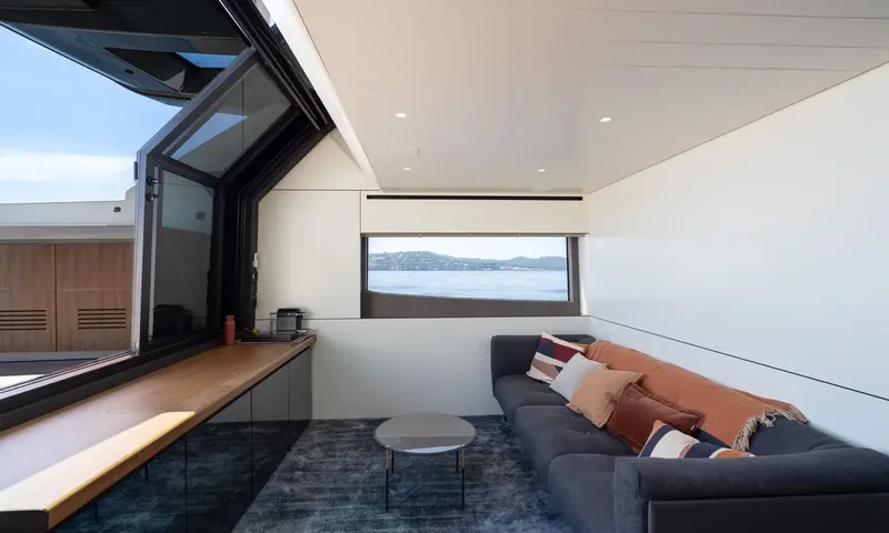 CC: Lounge with dark sofa, round coffee table, wooden counter and a folding window open