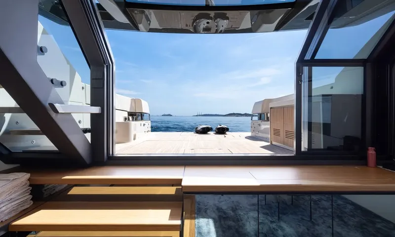 CC: View from the lounge through open glass onto a teak aft deck with two underwater scooters