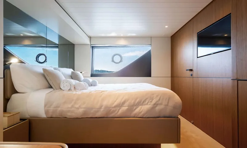 CC: Double cabin with white bedding, rolled towels, wood paneled wall and sea view windows