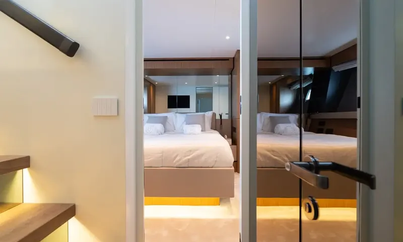CC: Doorway view into a cabin with a double bed and mirrored wall, stairs at left