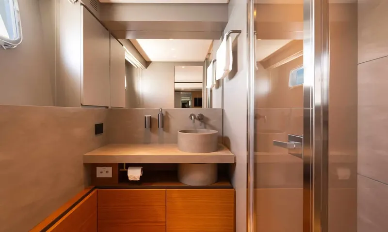 CC: Ensuite with round stone basin, wall mirror, wooden cabinets and glass shower door