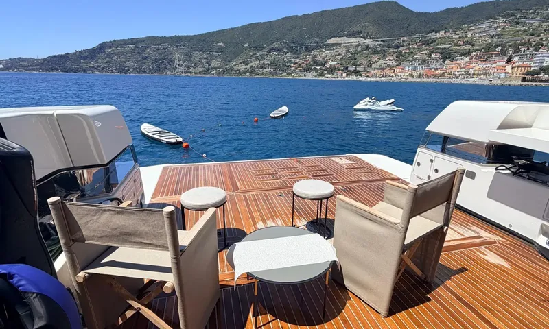 CC: Aft deck with folding chairs and table, paddleboards and a jet ski floating nearby