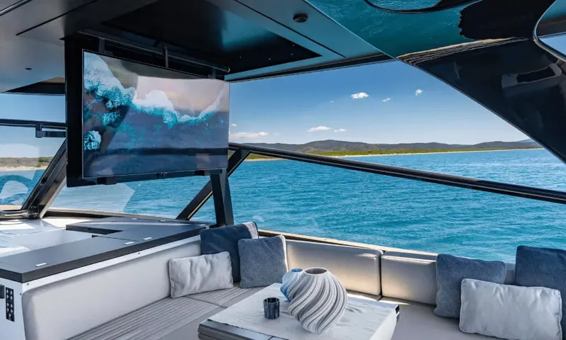 Dutch Pearl: Shaded lounge with cushioned sofa, coffee table and a large screen overlooking blue water