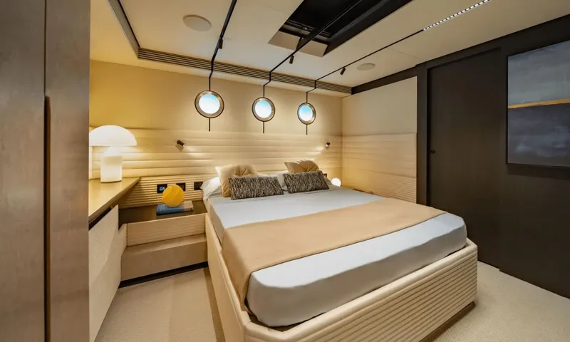 Dutch Pearl: Double cabin with beige bedding, three portholes above the headboard and a desk lamp