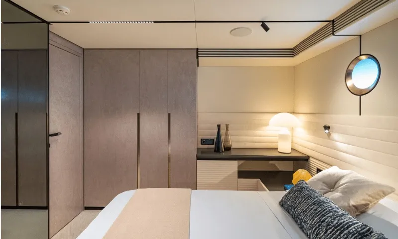 Dutch Pearl: Cabin with bed, tall wardrobes, desk with lamp and a round porthole