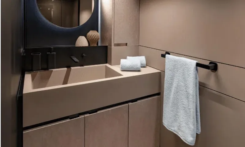 Dutch Pearl: Washroom with taupe basin, round mirror, folded towels and towel on a black rail
