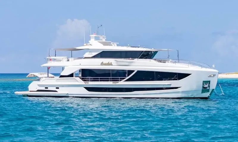 Louder: White motor yacht at anchor in turquoise water, seen from the side with a beach behind