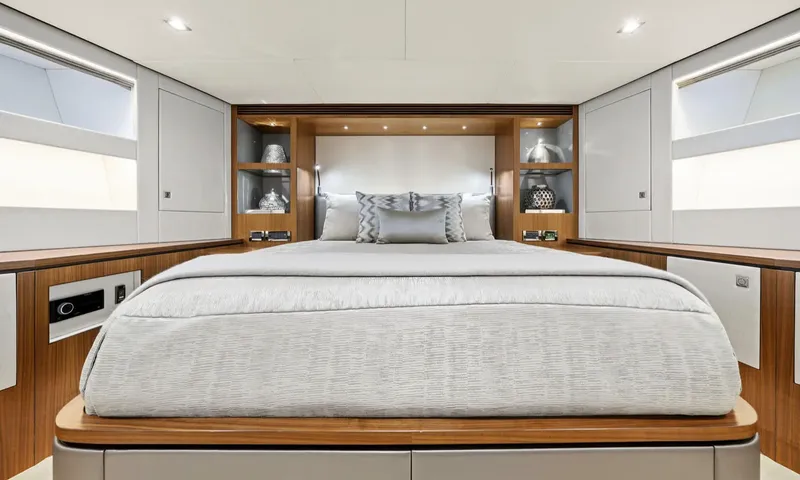 Louder: Cabin with double bed centred between wooden shelves and hull windows on both sides