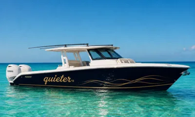 Louder: Dark hulled center console tender with twin outboard engines floating in clear turquoise water