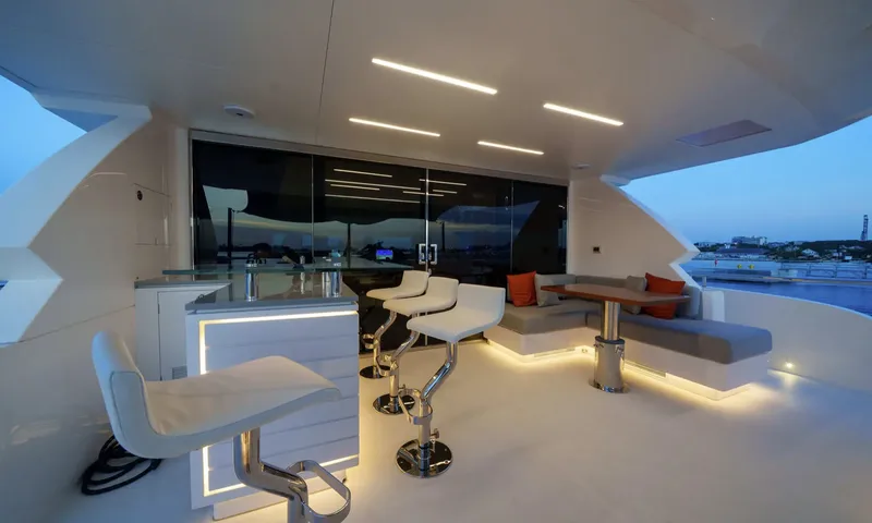 Louder: Upper deck bar with white stools and a lounge seating area lit at dusk