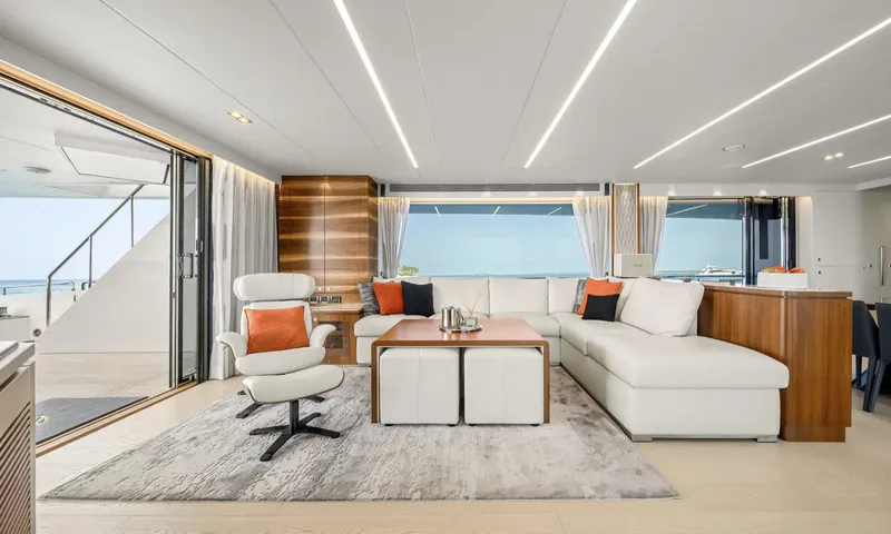Louder: Bright saloon with white sectional sofa, orange cushions, coffee table and sea views
