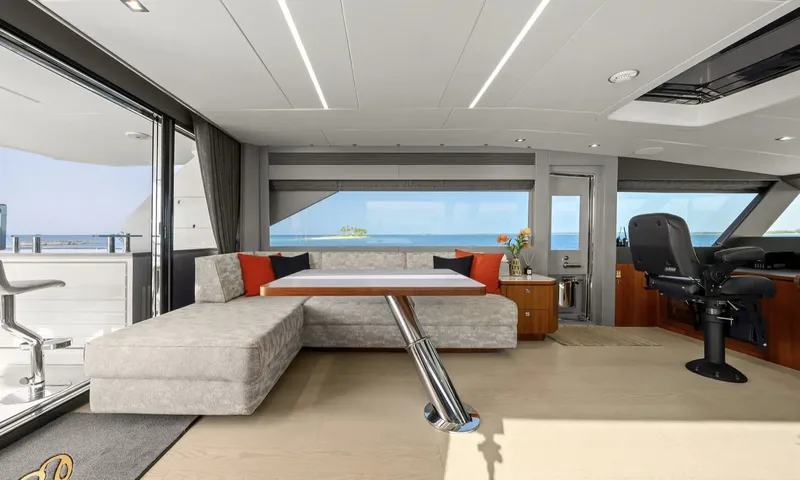 Louder: Wheelhouse with helm chair beside an L shaped sofa and table overlooking the sea
