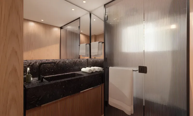 Aitana: Bathroom with black stone sink, mirror, rolled towels and ribbed glass shower door